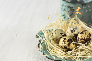 Quail eggs in a straw nest on a vintage platter, lit candle in the background, Easter, retro style, copyspace