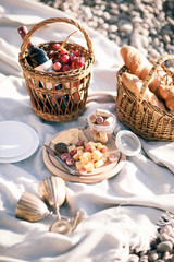 Picnic background with basket, wine and fruits by the ocean
