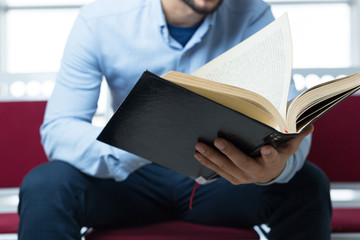 young male college student reading in the library