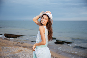 Happy woman in hat walking on the beach