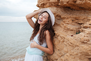 Happy woman standing near the rock on the beach