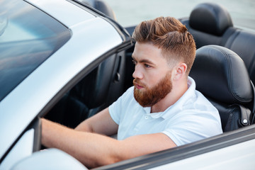 Handsome young bearded man driving his car