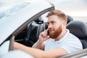 Young man driving his car and speaking on the cellphone