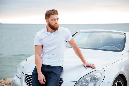 Young bearded man leaning on his car