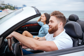 Joyful couple smiling while riding in their convertible car