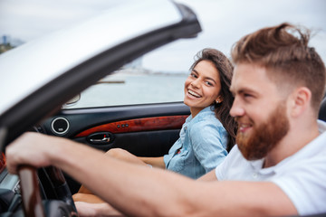 Joyful couple smiling while riding in their convertible car