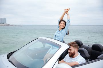 Young couple on road trip driving in convertible car