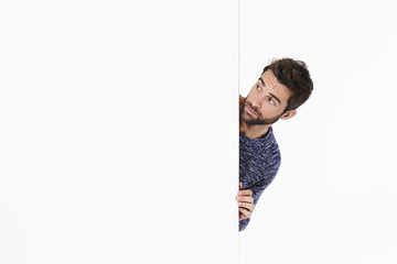 Curious guy looking around white wall