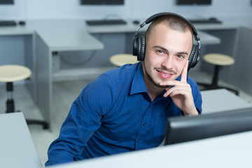 Young software engineer working in office with headphones on his