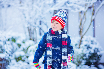 Happy kid boy having fun with snow in winter