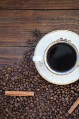 A cup of coffee. Coffee beans on the wooden background.
