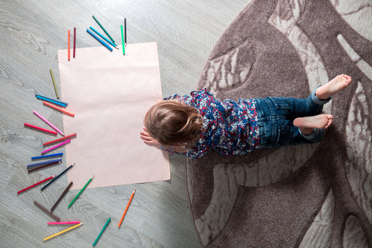 Little Girl Painting, Drawing. Child Lying On The Floor Near Crayons. Top View. Creativity Concept. Unrecognizable.