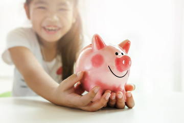 Little girl holding a piggy bank while relaxing at home