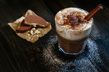 hot chocolate with chocolate wafers on the black table