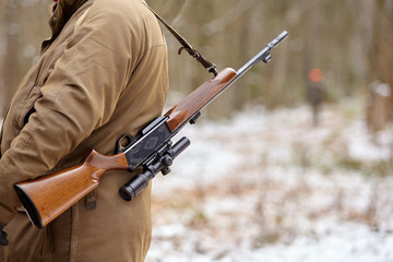 Hunter in camouflage with rifle. Winter hunting.