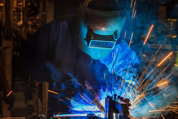 worker with protective mask welding in factory