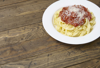 A dinner dish of spaghetti Bolognese on a rustic wooden table top background with empty space at side