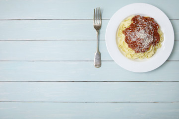 A dinner dish of spaghetti Bolognese on a blue wooden table top background with blank space at side