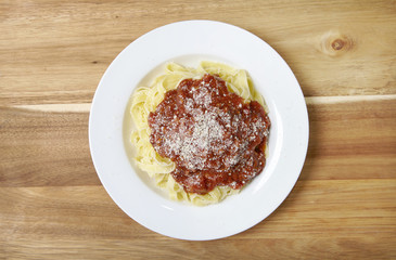 A dinner dish of spaghetti Bolognese on a wooden counter top background