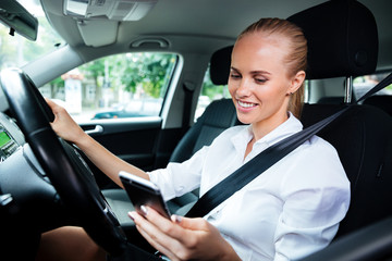 Fototapeta na wymiar Smiling business woman dialing phone number while driving car