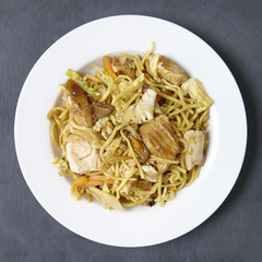 Aerial view of a dinner dish of chicken noodle stir fry on a rustic slate background