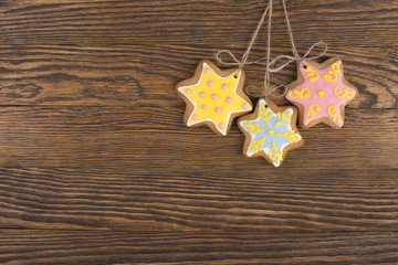 Gingerbread cookies hanging over wooden background. Christmas decorations top view with copy space. Prepare for xmas eve or other winter holidays