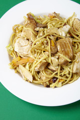 A dinner dish of chicken noodle stir fry on a green background