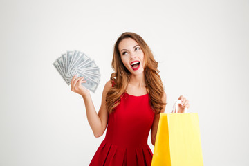 Happy woman in red dress holding shopping bag and money