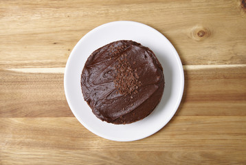 A whole chocolate fudge layer cake on a wooden kitchen counter background
