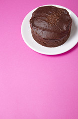 A whole chocolate fudge layer cake on a hot pink background with blank space below