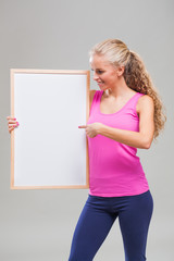 Studio shot image of young sporty woman who is pointing on blank space for your advertisement.
