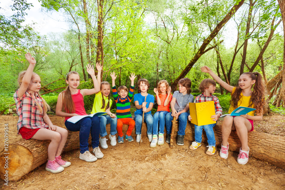 Wall mural Cute kids reading books outdoor sitting on the log