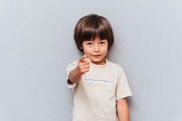 Smiling little boy standing and pointing on you