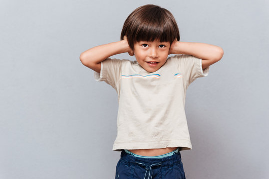 Cute little boy covered ears by hands