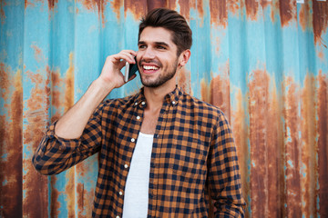 Cheerful young man standing and talking on mobile phone