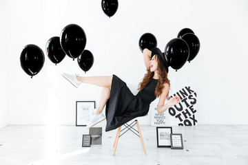 Cheerful woman having fun over white background with black balloons