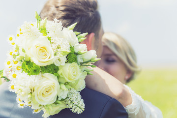 Brautpaar küsst sich mit Blumenstrauß