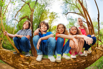 Kids sitting on trunk of fallen tree in the forest