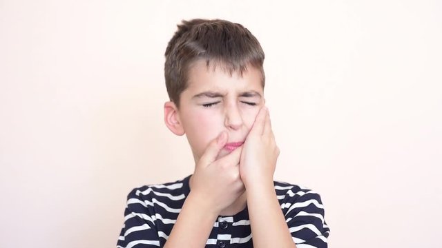 Young boy with toothache holding her cheek