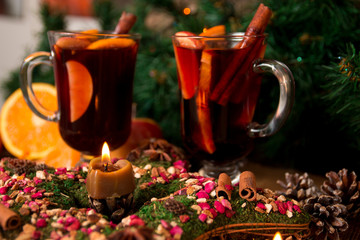 Christmas mulled wine and star, candles  on wooden table. Xmas decorations in background. Winter warming drink. Two glasses.