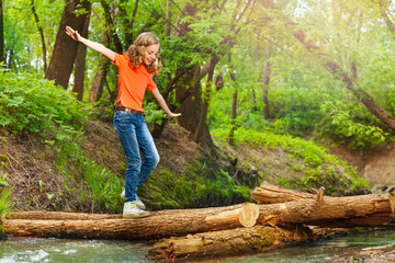 Cute girl balancing while crossing a log bridge