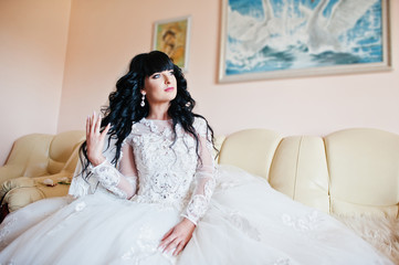 Fototapeta premium Gorgeous brunette bride sitting on leather couch at her room on
