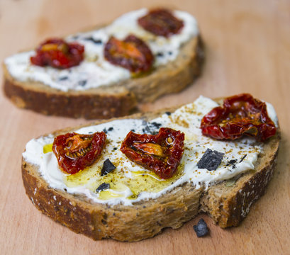 Sandwiches with soft cheese, dried tomatoes and black salt