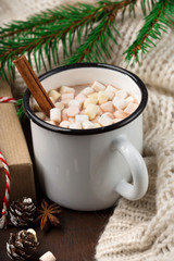 Cup with homemade Christmas hot Chocolate drink, Marshmallows and Holiday Gift on dark background. Winter time concept. Selective focus