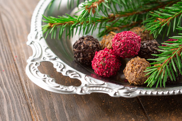 Obraz na płótnie Canvas Assorted dark chocolate truffles with dried strawberry pieces and chopped hazelnuts on rustic wooden background, selective focus. Christmas time
