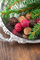 Obraz na płótnie Canvas Assorted dark chocolate truffles with dried strawberry pieces and chopped hazelnuts on rustic wooden background, selective focus. Christmas time, Holiday concept