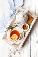 Tray with cup of hot black tea, lemon and honey on white rustic wooden background. Breakfast concept, top view