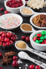Christmas baking cupcake decorations and sprinkles, black background, selective focus.
