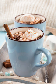 Blue Cups of hot Chocolate drink with Marshmallows and cinnamon on blue wooden background. Winter time. Holiday concept