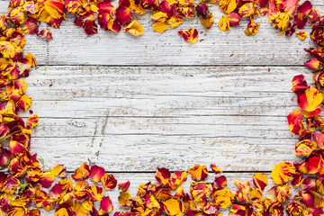 Dry petals of rose on a white wooden background